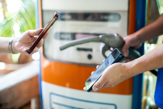 Selective focus to customer using smartphone for contactless mobile payment at a gas station pump