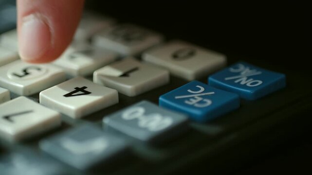 Extreme close up of a person's finger turning on a calculator and pressing the number four on the keypad, illustrating financial calculation, accounting, and business mathematics
