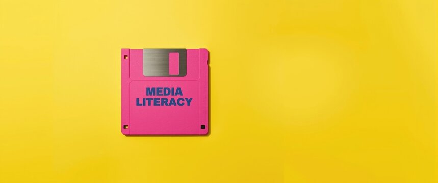 Pink Floppy Disk with Media Literacy Text on Yellow Background