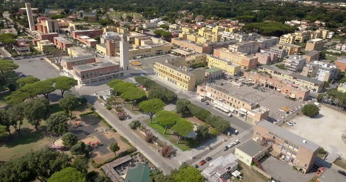 Aerial view of the historic center of Sabaudia, in the province of Latina, in Lazio, Italy. Rationalist architecture from the 1930s includes a church bell tower, surrounded by a green public park.