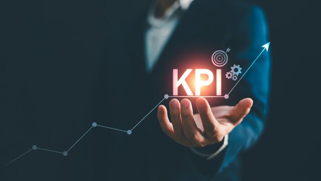 Businessman hand holding glowing KPI text with rising growth graph line arrow and target icon. Concept for key performance indicator, business performance, goal measurement, evaluation, success