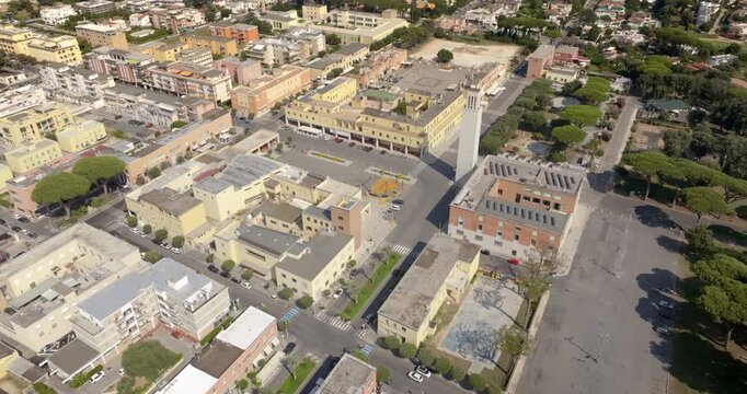 Aerial view of Sabaudia historic town center in Italy showing the iconic rationalist civic tower, municipal buildings, main piazza and surrounding streets in a summer sunny morning.