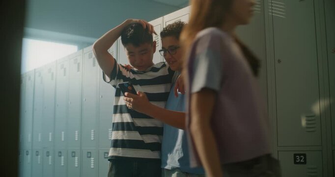 Two Cheerful Teenage Classmates Stand by School Lockers, Sharing Smartphone and Laughing Together Before Class. Concept of Authentic Gen Z Lifestyle, Friendship and Positive Social Interaction.