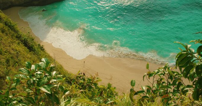 White ocean waves washing over golden sand at Kelingking Beach Nusa Penida Bali