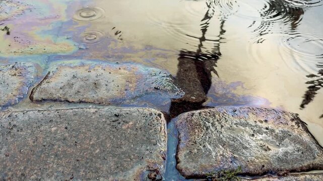 Oil Leak Colours Swirling in a Rain Puddle on the Road