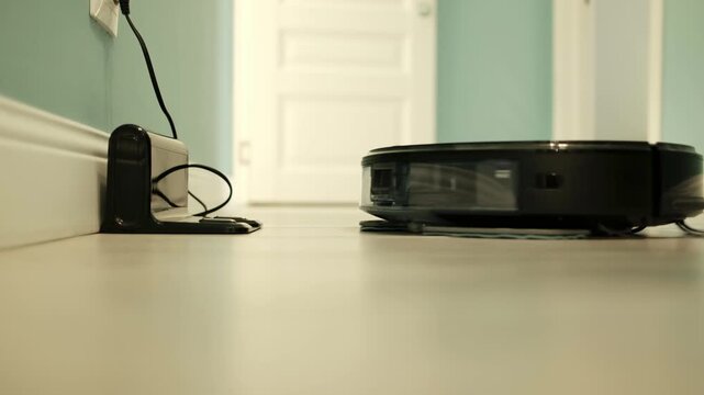 Smart robotic vacuum cleaner automatically leaving its charging dock and starting a cleaning cycle inside a modern home. Autonomous household appliance technology demonstrates automated floor cleaning