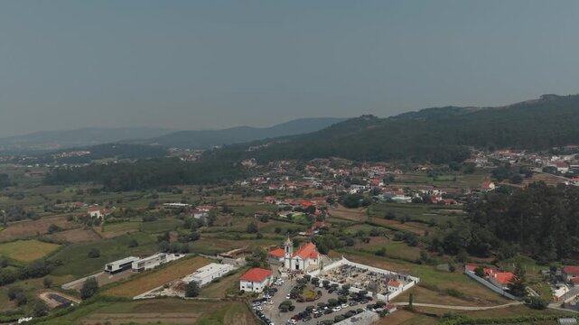 Aerial view of Igreja Paroquial de Santo Andre de Palme surrounded by rural landscape and green hills in Palme, Braga, Portugal.