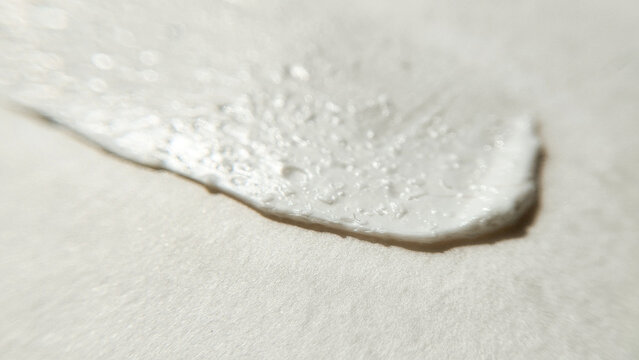 A thick stroke of white cosmetic cream with soft texture waves. Skincare product sample swatch, minimalist beauty background.
