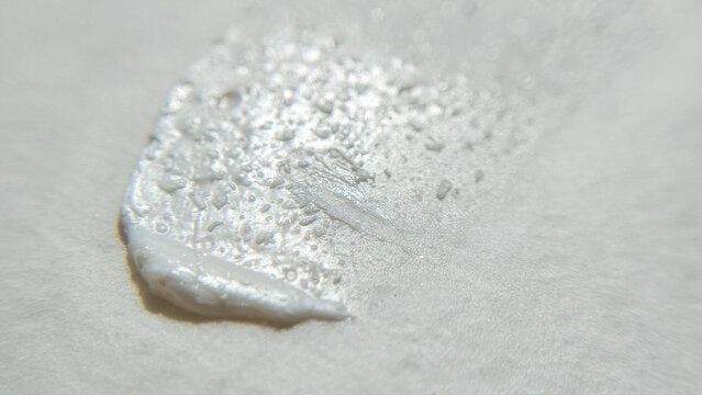 A thick patch of white cosmetic cream with a fine textured surface. Skincare sample swatch, minimal aesthetic beauty backdrop.