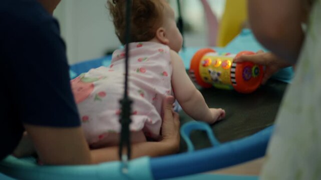 Baby with curly hair learning to crawl during developmental therapy session, supported by a therapist promoting motor skills