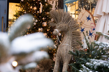 Decorative Christmas straw horse stands among holiday trees in a shop window during winter © ir1ska