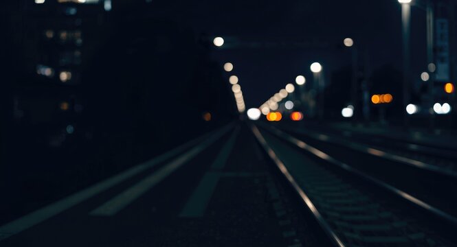 Train Tracks Leading into a Distant City at Night with Soft Bokeh Lights