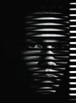 Dramatic black and white portrait with strong shadows and light from blinds