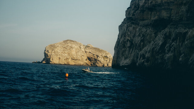 boat sailing past rock in the sea