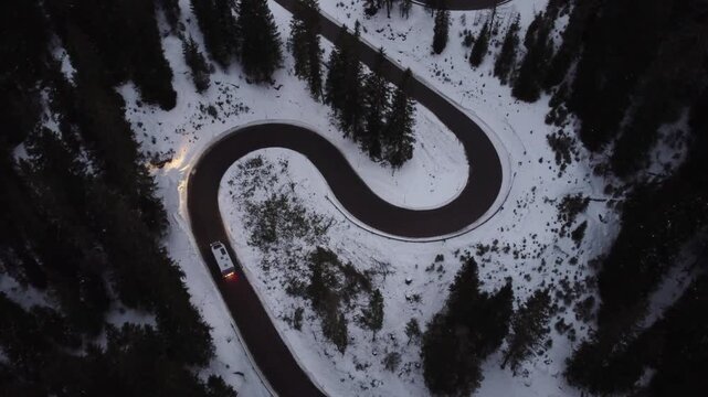 Aerial view of a winding road through a snowy forest at Passo Giau in Colle Santa Lucia, Veneto, Italy.