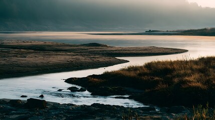 Fototapeta premium A serene river flows gently around a sandy bend under soft warm ambient light creating a tranquil landscape with subtle tonal contrast