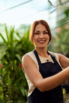 Smiling Female Gardener in Greenhouse Wearing Apron &mdash; Small Business Entrepreneur and Plant Care Professional