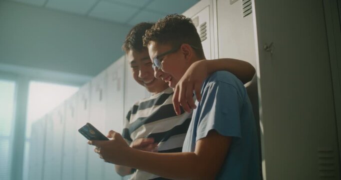 Close Friends Gather beside Personal Lockers, Looking at Content on Smartphone and Enjoying Lighthearted Moment Between Classes. Student Friendship, Digital Communication, Social Side of School Life.