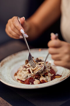 Woman Eating Creamy Pasta With Fork at Restaurant Table, Gourmet Dining and Lifestyle Moment