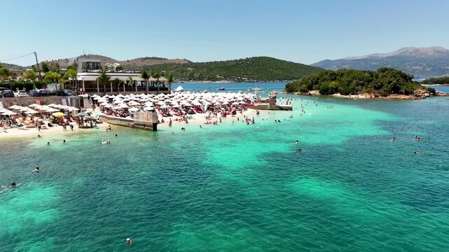 Aerial view of the best beach in Ksamil, crystal clear sea, Ionian Sea, Saranda, Albania. Drone view from above. Sandy beach and people relaxing in sea. Summer destination on the Mediterranean Sea, Eu