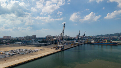 Obraz premium Industrial Port with Cranes and Cargo Vessel Under Blue Sky
