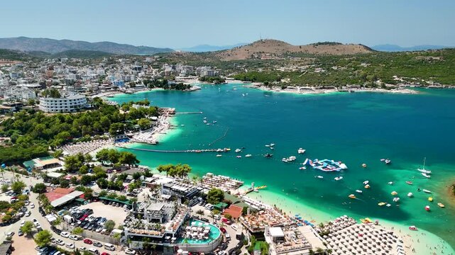 Aerial view of the best beach in Ksamil, hotels and beach bars, crystal clear sea, Ionian Sea, Saranda, Albania. Drone view from above. Sea and coast with sandy beach. Summer destination on the Medite