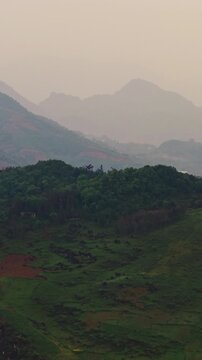 Lush Green Hills And Dense Forest With Misty Background In Sapa, Vietnam. - aerial vertical shot