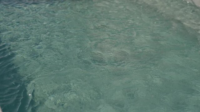 Sunlit Ripples Moving Across Clear Turquoise Water Above A Pale Sandy Bottom