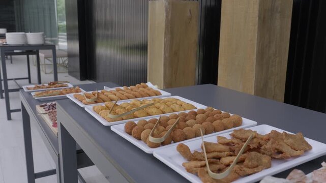 White Trays Of Croquetes Rissois And Fried Snacks With Tongs On A Grey Buffet Table