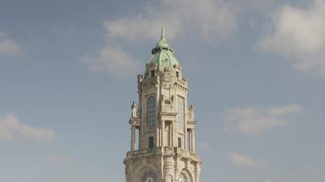 Stone clock tower with green copper dome rising above blue sky in Porto Portugal
