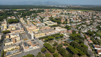 Fototapeta premium Aerial view of the historic center of Sabaudia, in the province of Latina, in Lazio, Italy. Rationalist architecture from the 1930s includes a church bell tower, surrounded by a green public park.