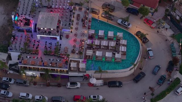Aerial view of illuminated beach club with swimming pool and lounge area at night in Ksamil, Vlore County, Albania.