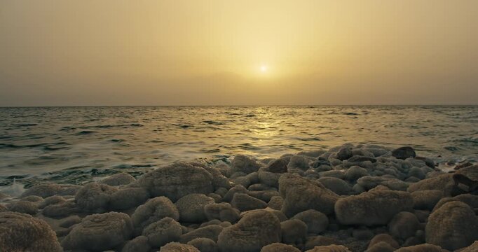 Dead Sea salt covered shoreline in Jordan at sunset with calm waves, golden light, and a tranquil hypersaline landscape.
