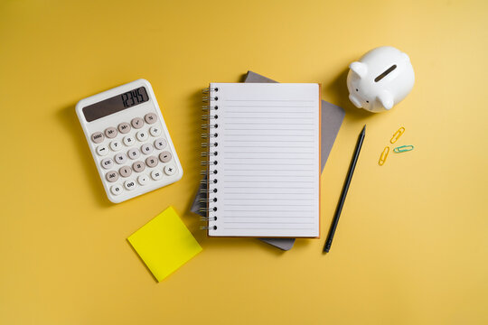 Personal financial planning with calculator, notebook and sticky note on yellow background, flat lay with copy space