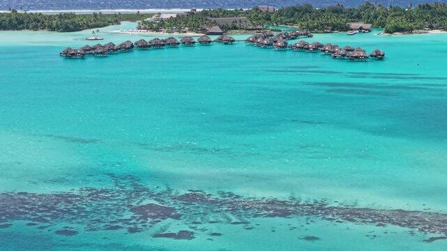 Bora Bora, French Polynesia. Revealing Drone Shot of Luxury Resort Bungalows Over Turquoise Lagoon Water