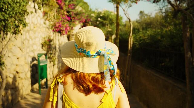 A female tourist walks along a street on the island of Capri near luxury hotels
