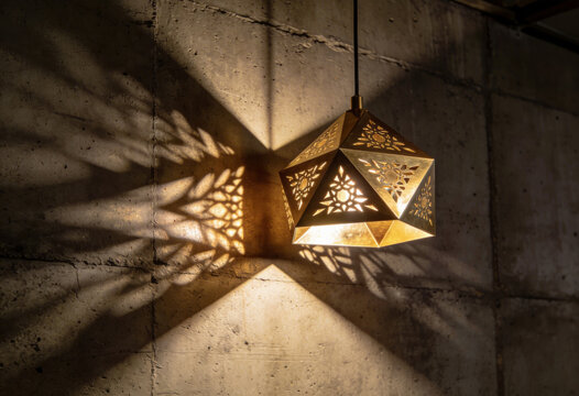 Brass geometric pendant lamp casting decorative patterned shadows on a concrete wall for dramatic interior background and ambient lighting banner