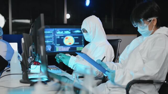 Scientist in protective suit analyzes neurological data and biological samples using a modern microscope in a high tech laboratory.