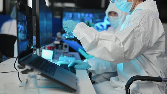 Scientist in protective suit analyzes neurological data and biological samples using a modern microscope in a high tech laboratory.