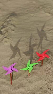 Colorful pinwheels spinning on a sandy beach with shadows