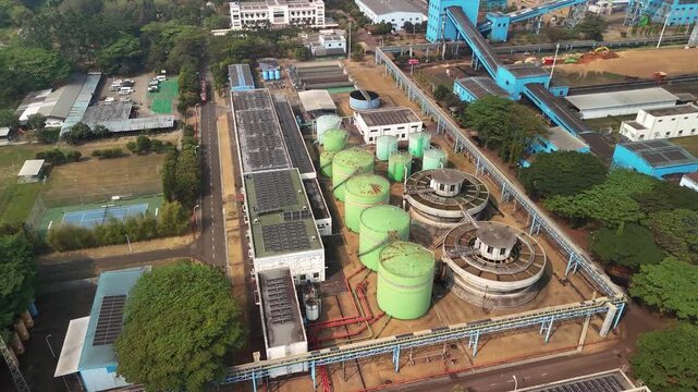Aerial view of industrial facility with green storage tanks and circular clarifiers