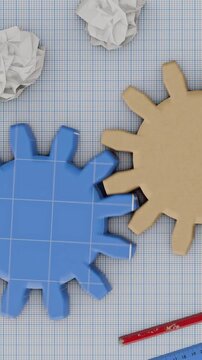 Interlocking gears on graph paper with crumpled paper and pencils