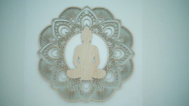 Wooden Buddha silhouette meditating with a spiritual mandala background on a light wall, symbolizing peace, zen, and mindfulness