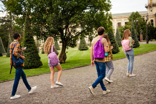 High school students and friends walking on campus with colorful backpacks on a sunny day