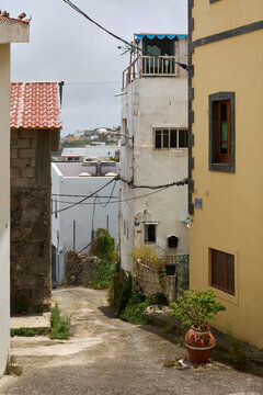 View down the Pasaje Arias, a narrow sloping street lined with traditional buildings and plants in Firgas, Gran Canaria.