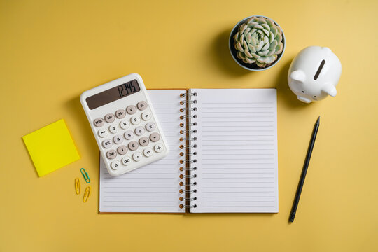 Household budgeting and savings planning with calculator, open notebook for notes and piggy bank, flat lay mockup