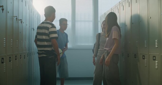Four Teenage Classmates Stand Together in School Locker Room, Chatting, Laughing, and Enjoying Casual Conversation Between Classes. Concept of Positive Peer Interaction in Modern School Environment.