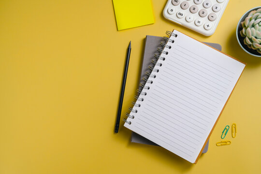 Business financial analysis with calculator and notebook on yellow background, flat lay with copy space