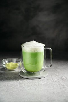 Matcha latte with frothy milk and green tea powder in glass cup. Healthy food, nutrition and antioxidant on dark background with copy space