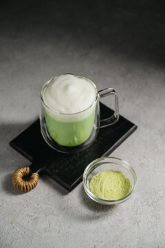 Matcha latte with green tea powder and frothy milk, matcha preparation and healthy beverage concept